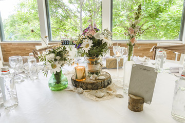 Round wedding table with forest theme, decoration, plates, forks, and glasses.
