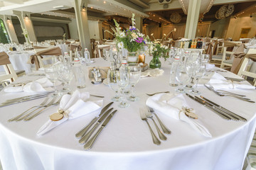 Round wedding table with forest theme, decoration, plates, forks, and glasses.