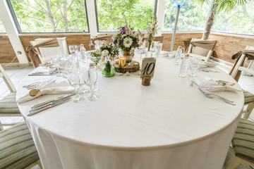 Fototapeta na wymiar Round wedding table with forest theme, decoration, plates, forks, and glasses.