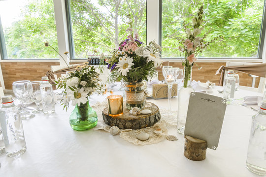 Round wedding table with forest theme, decoration, plates, forks, and glasses.