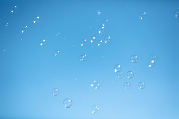 Soap bubbles in flight against the blue sky