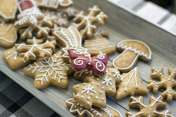 Painted traditional Christmas gingerbreads arranged on wooden tray in daylight, snowflakes and other Xmas symbols