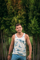 Smiled man in shorts and shirt in summer time walks near the park