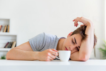 Obraz na płótnie Canvas Young man drinking coffee and having breakfast