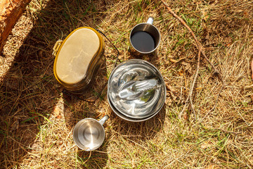 Set of camping cooking equipment on the dry grass in the forest