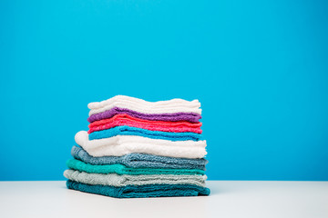 Fototapeta na wymiar Photo of stacks multi-colored towels on empty blue background.