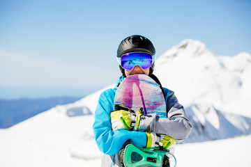 Photo of woman tourist in helmet looking into camera with snowboard in hands