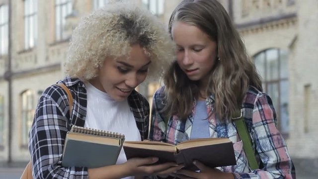 Surprised adolescent girls studens finding new important information in old book