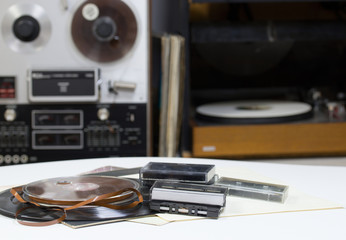 Vinyl record with copy space in front of a collection albums dummy titles. Reel Tape Recorder. Audio cassetes tap.
