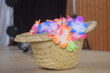 Fototapeta na wymiar Sommerlicher Strohhot mit neonfarbener Partykette aus Blumen Deko