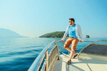 success man standing at nose of boat with sea and mountains on background