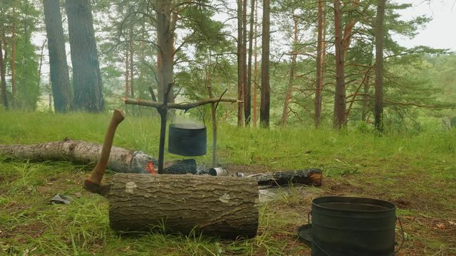 Cauldron is on camp fire in forest.