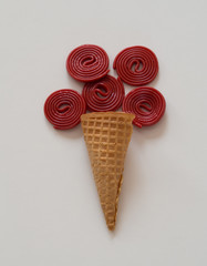Red licorice and ice cream cone composition on white background