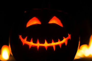 Close up portrait of carved pumpkin head Jack-o-lantern. Terrible smiling symbol with eyes and scary grin. Halloween party art decoration. Silhouette of facial features in fire.