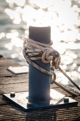mooring bollard with a rope and a knot in front of water