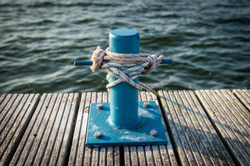 Fototapeta premium mooring bollard with a rope and a knot in front of water