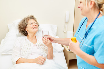 Fototapeta premium Pflegekraft gibt Senior Frau ein Medikament