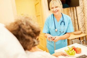 Pflegedienst Frau bringt Seniorin Frühstück