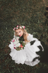 overhead view of beautiful young bride holding bouquet of flowers and looking at camera