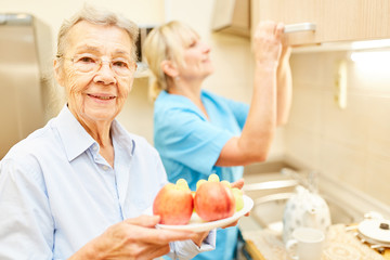 Alte Frau mit einem Teller Obst in der Küche