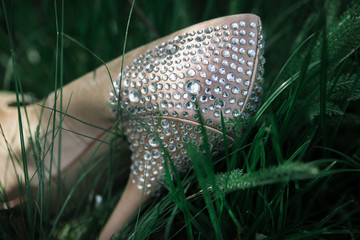 stylish silk bride shoes with crystals lies on grass. close up
