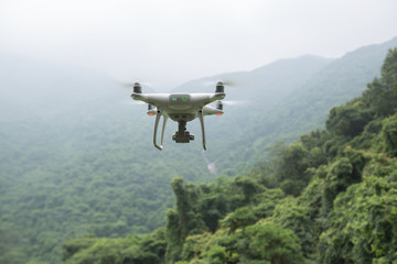 White drone with camera flying over forest