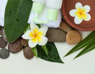 Spa or wellness background with white towels, tropical leaves, flowers, body and face care tools, stones and accessories on white background, top view.