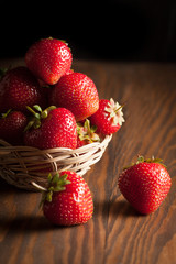 Macro photo of fresh ripe red strawberry in a wooden bowl on rustic background. Organic natural products.