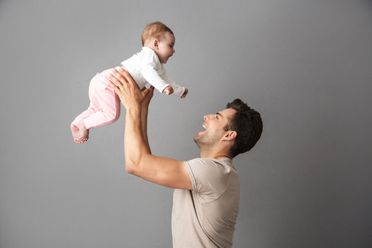 Image of happy father man holding his little child in hands, isolated over gray background