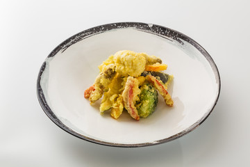 vegetables in a batter in a plate isolated on a white background