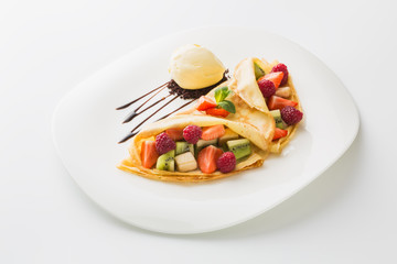 dessert of berries and fruit with ice cream wrapped in a pancake in a plate isolated on white background