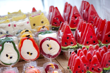 Natural honey sourced sweet candy in different shapes of fruits and colorful designs at a local state fair. Watermelon, pear, apple lollipop or jelly candy  
