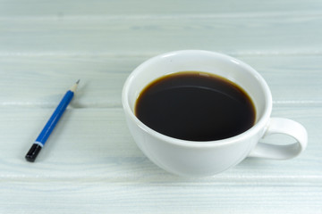 Hot coffee in the morning write new ideas .Props decorations a blue pencil on a white wooden floor background,.Top view Copy Space.