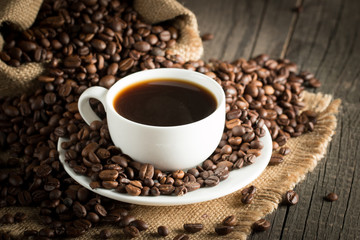 Coffee cup and beans on a rustic background. Coffee Espresso and a piece of cake with a curl. Cup of Coffee and coffee beans on table.