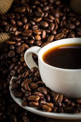 Coffee cup and beans on a rustic background. Coffee Espresso and a piece of cake with a curl. Cup of Coffee and coffee beans on table.