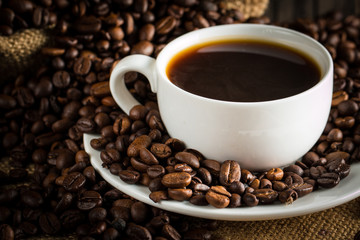 Coffee cup and beans on a rustic background. Coffee Espresso and a piece of cake with a curl. Cup of Coffee and coffee beans on table.