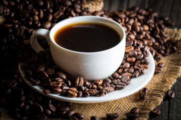 Coffee cup and beans on a rustic background. Coffee Espresso and a piece of cake with a curl. Cup of Coffee and coffee beans on table.