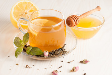 Closeup of cup of tea with tea leaves, mint on vintage wooden background. Black herbal tea with...