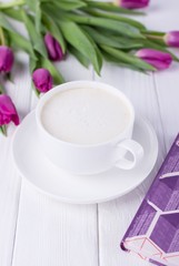 Coffee cappuccino, book and purple tulips on a white background