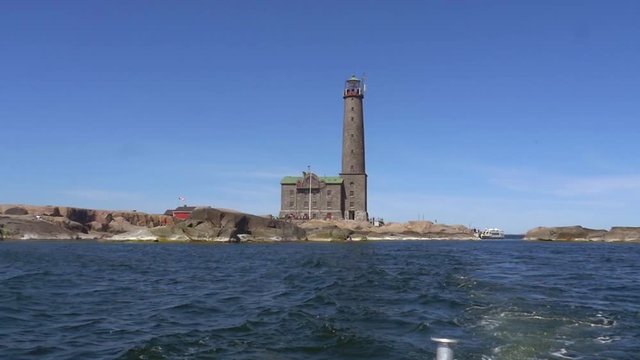 Pov view from a boat of a huge lighthouse, on a rocky island bengtskar, on a sunny summer day, in saaristomeri national park of the finnish archipelago, in Varsinais-suomi, Finland