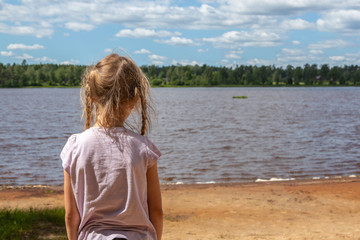 Flicka står på strand vid en insjö