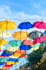 Obraz na płótnie Canvas Different colorful umbrellas hanging over the street against sky