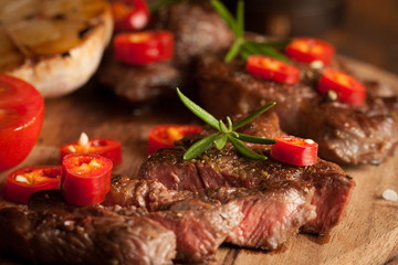 grilled fillet steak with tomatoes and roast vegetables on an old wooden board, background.