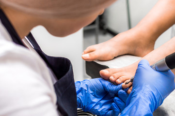 Fototapeta na wymiar Female feet on towel roll. Nails getting a fresh and accurate look during a pedicure procedure.