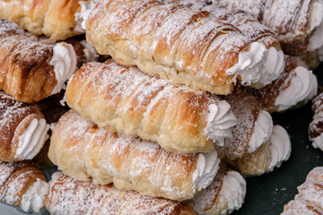 Austrian puff rolls with vanilla cream and powdered sugar at the market of street food. close up
