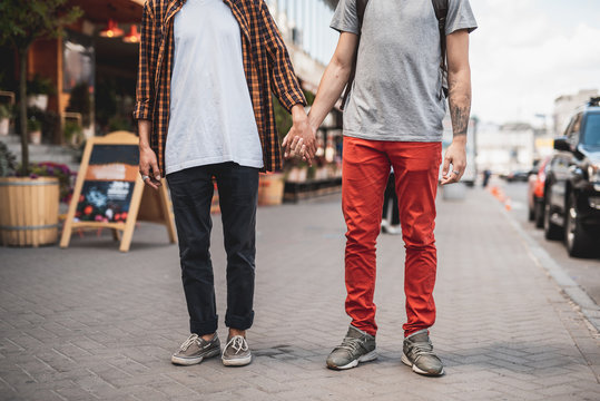 Man holding hand of friend while standing on sidewalk on street. Comrades spending time together concept