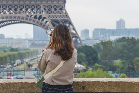 Young women taking picture of Eiffel tower, back view