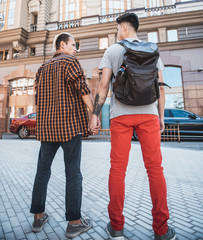 Full length side view calm man telling with serene friend while holding him with arm. They standing...