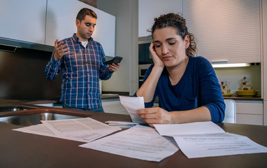 Desperate young couple with many debts reviewing their bills. Financial family problems concept.