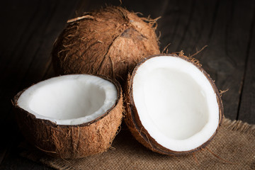 Ripe half cut coconut on a wooden background.  Coconut cream and oil.